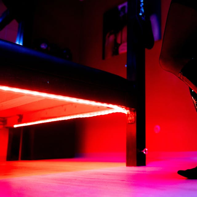 Eine Prostituierte steht vor der roten Beleuchtung unter einem Bett in einem Studio. Foto: picture alliance/dpa