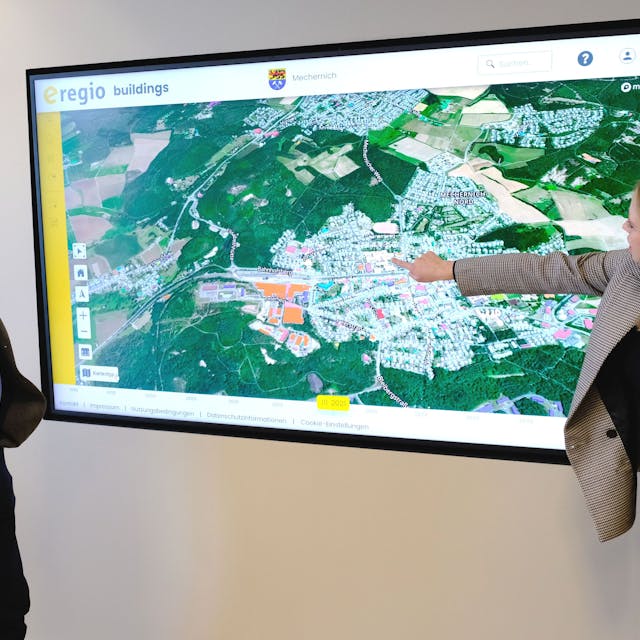 Geschäftsführer Markus Böhm und Mitarbeiterin Miriam Stork vom Euskirchener Energieversorger e-regio vor einer Ansicht des digitalen Zwillings zur Erstellung der Kommunalen Wärmeplanung für die Stadt Mechernich.