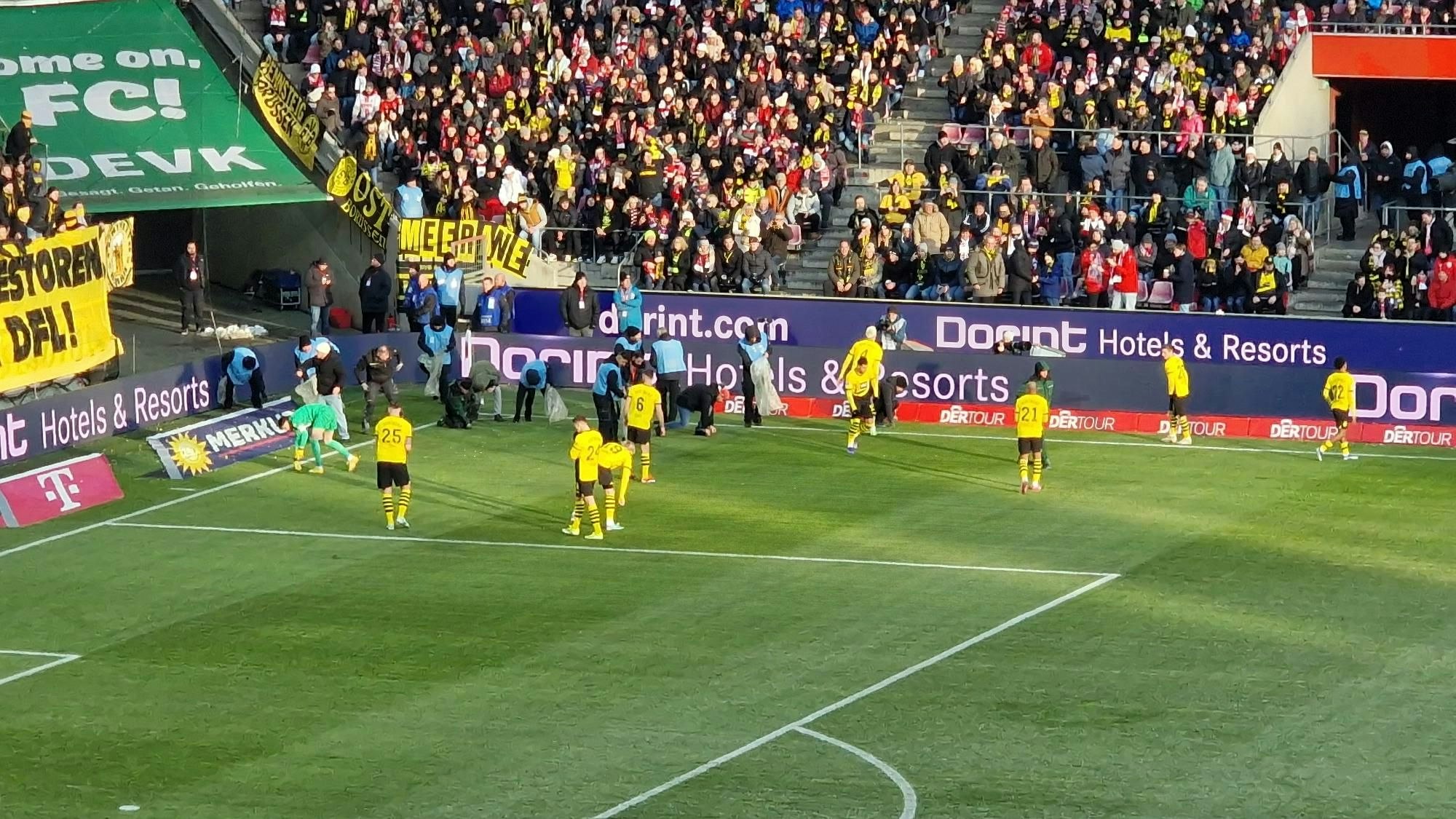 Die Dortmunder Spieler sammeln die aus Protest von ihren Fans geworfenen Schokotaler ein.