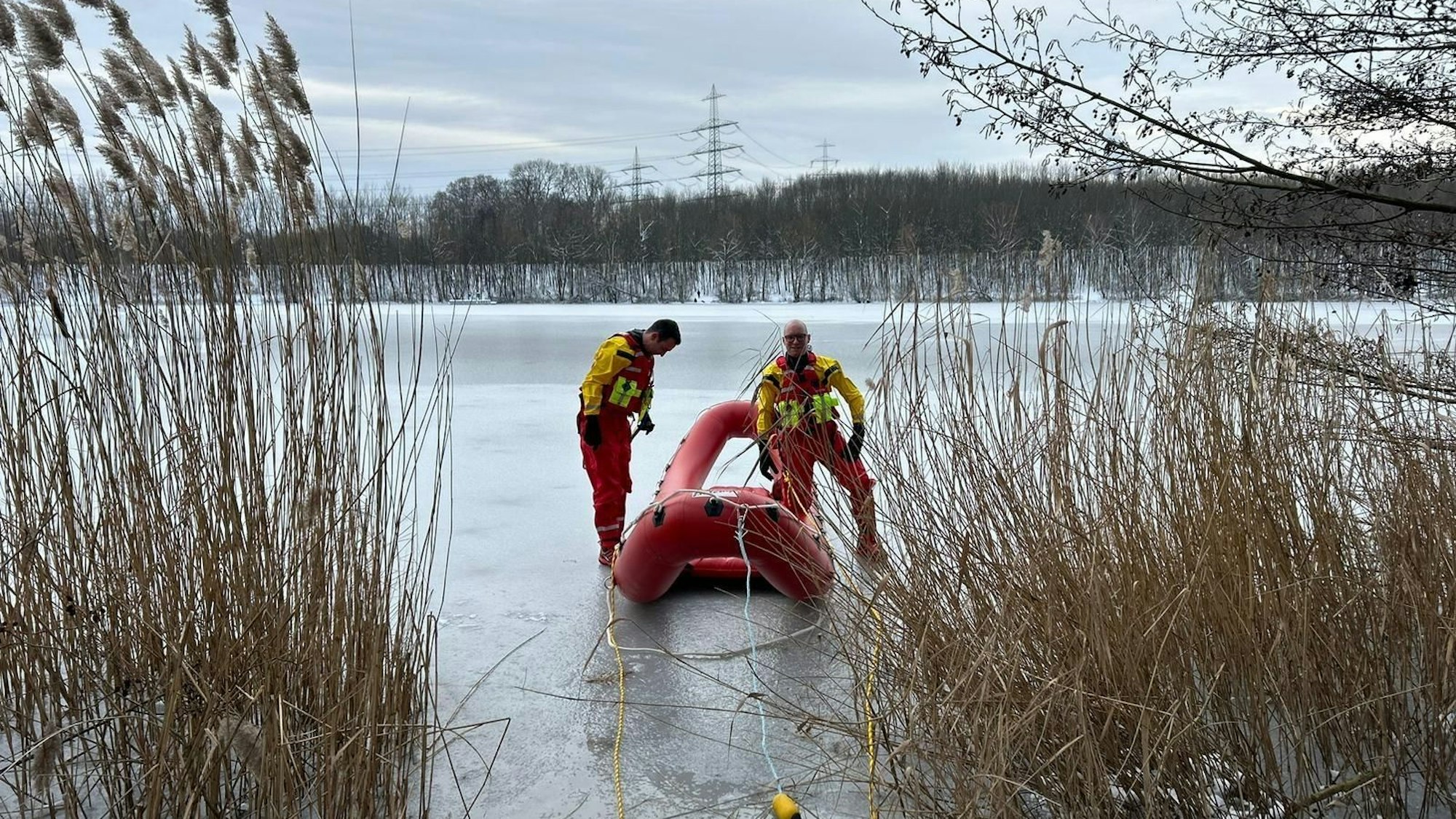 Ein Schlauchboot und zwei Feuerwehrmänner auf einem vereisten See.