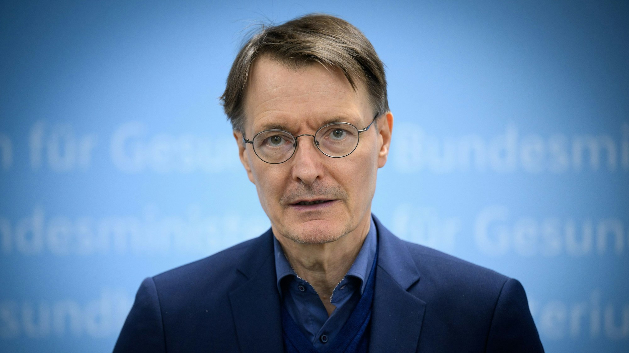 Karl Lauterbach (SPD), Bundesminister für Gesundheit, ist vor einem blauen Hintergrund zu sehen.