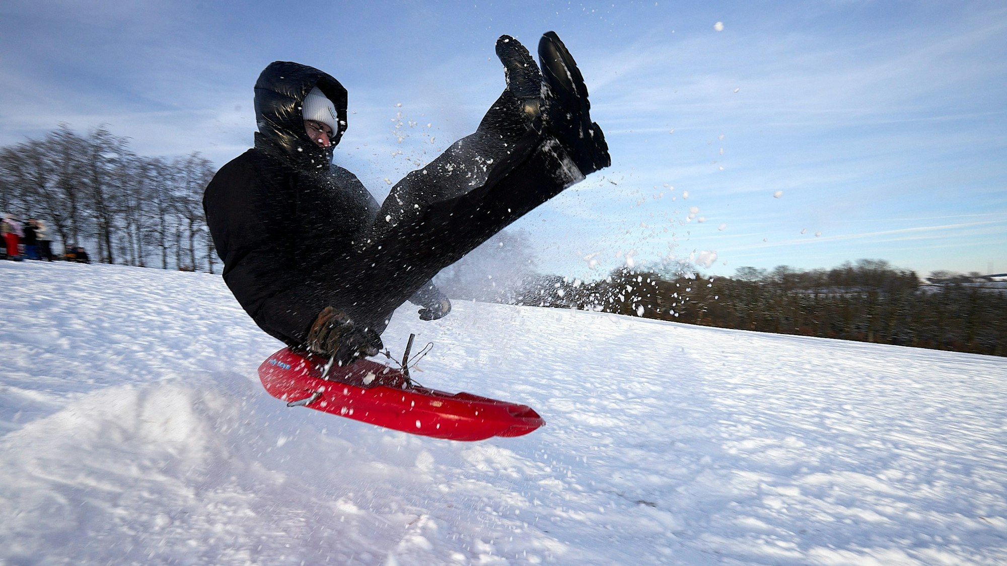 Ein junger Wintersportler macht auf seinem Plastikbob einen kräftigen Sprung.