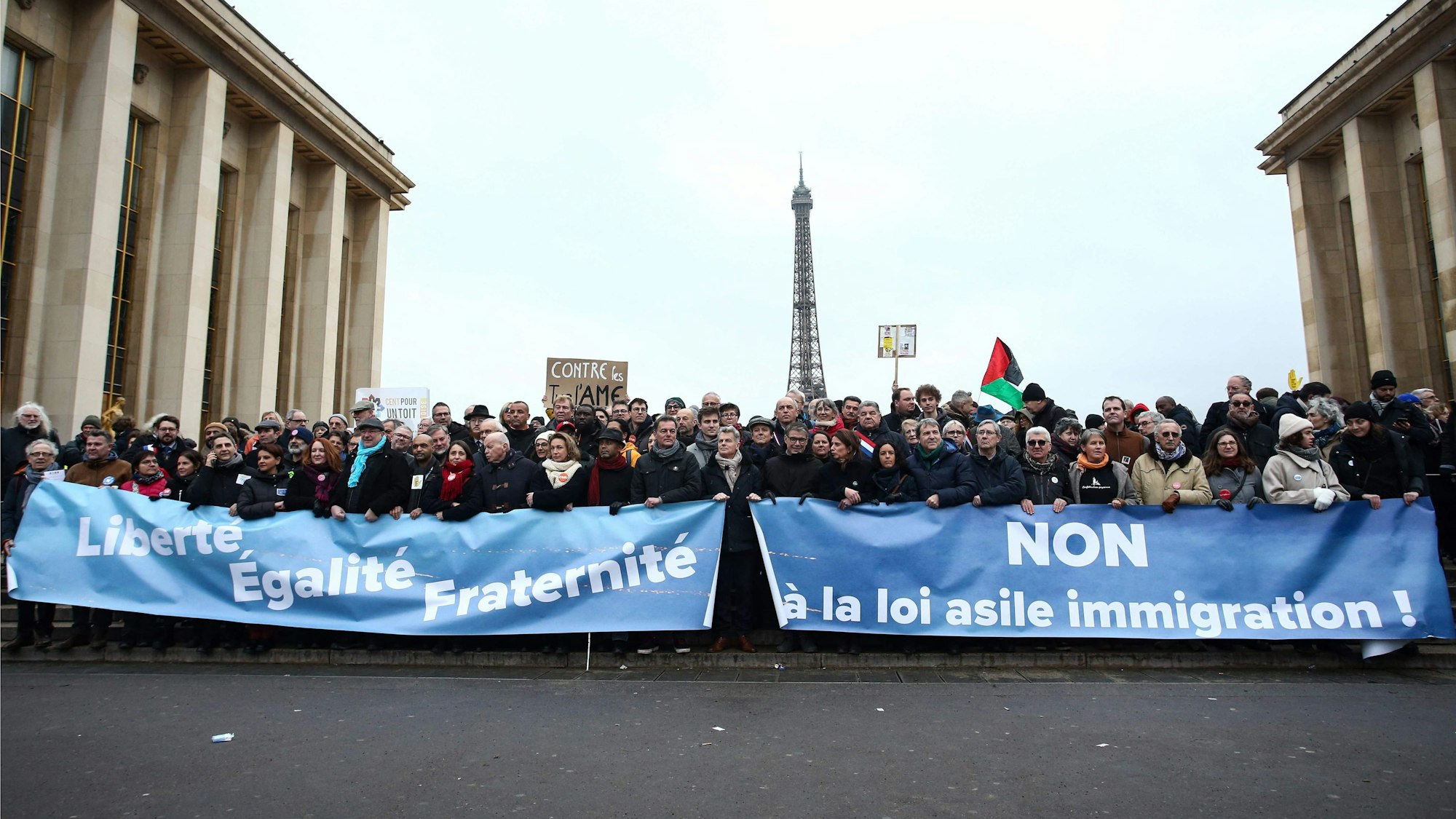 Demonstranten stehen mit Transparenten mit der Aufschrift ‚Freiheit, Gleichheit, Brüderlichkeit‘ (l) und ‚Nein zum Asyl-Einwanderungsgesetz‘ bei einer Demonstration gegen das kürzlich verabschiedete französische Einwanderungsgesetz.