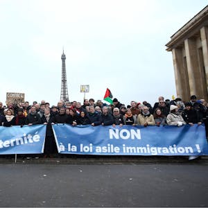 Demonstranten stehen mit Transparenten mit der Aufschrift ‚Freiheit, Gleichheit, Brüderlichkeit‘ (l) und ‚Nein zum Asyl-Einwanderungsgesetz‘ bei einer Demonstration gegen das kürzlich verabschiedete französische Einwanderungsgesetz.
