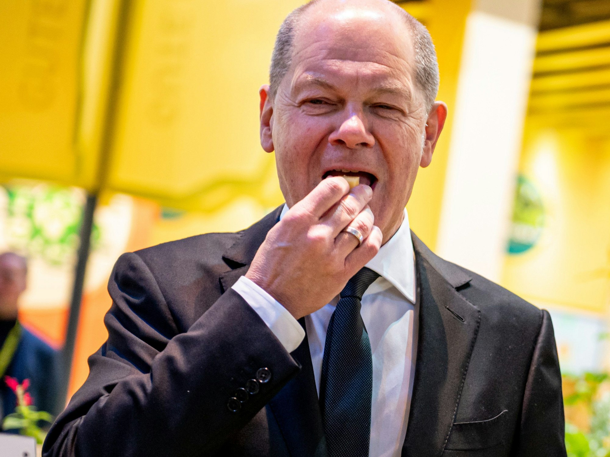 Bundeskanzler Olaf Scholz (SPD) probiert auf der Grünen Woche am Stand für  Ökolandbau ein Stück Käse.