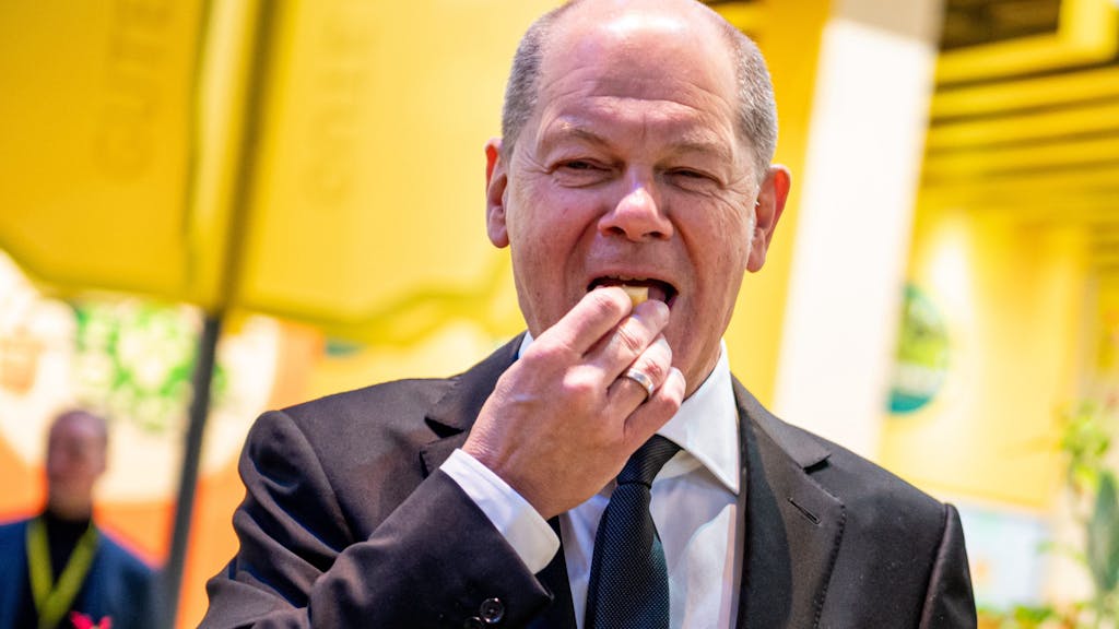 Bundeskanzler Olaf Scholz (SPD) probiert auf der Grünen Woche am Stand für  Ökolandbau ein Stück Käse.&nbsp;