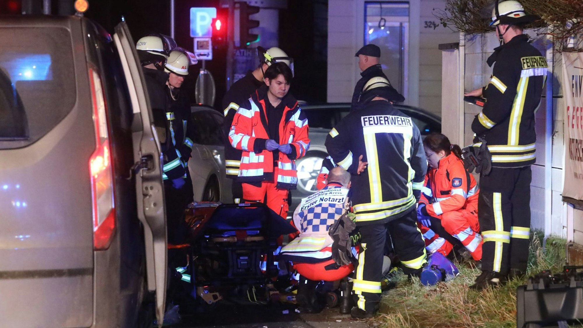 Rettungssanitäter und ein Notarzt beugen sich über einen Verletzten, Feuerwehrleute schauen bei dem Einsatz zu.