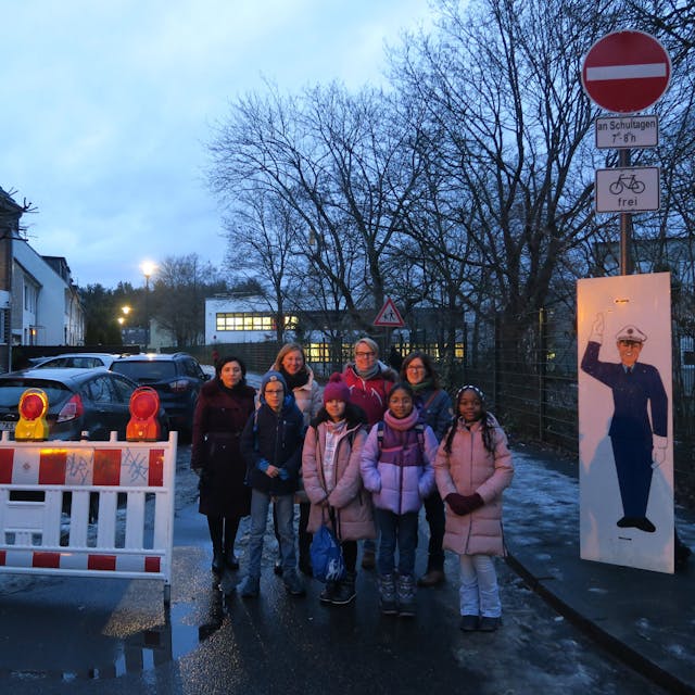 Kinder stehen an einer Straßenabsperrung.