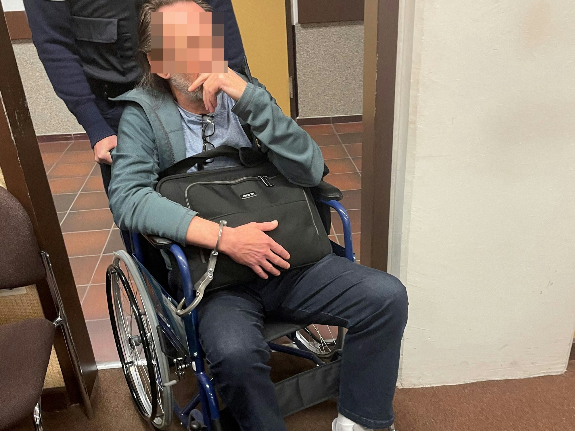 Der mutmaßliche Drach-Komplize Eugen W. wurde zuvor an den Rollstuhl gefesselt in den Gerichtssaal gebracht.
