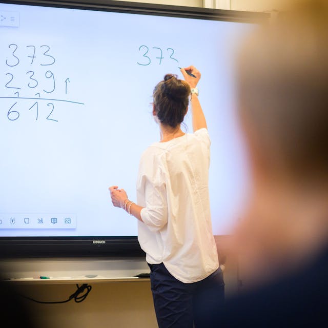 Eine Lehrerin rechnet an einer digitalen Tafel.&nbsp;