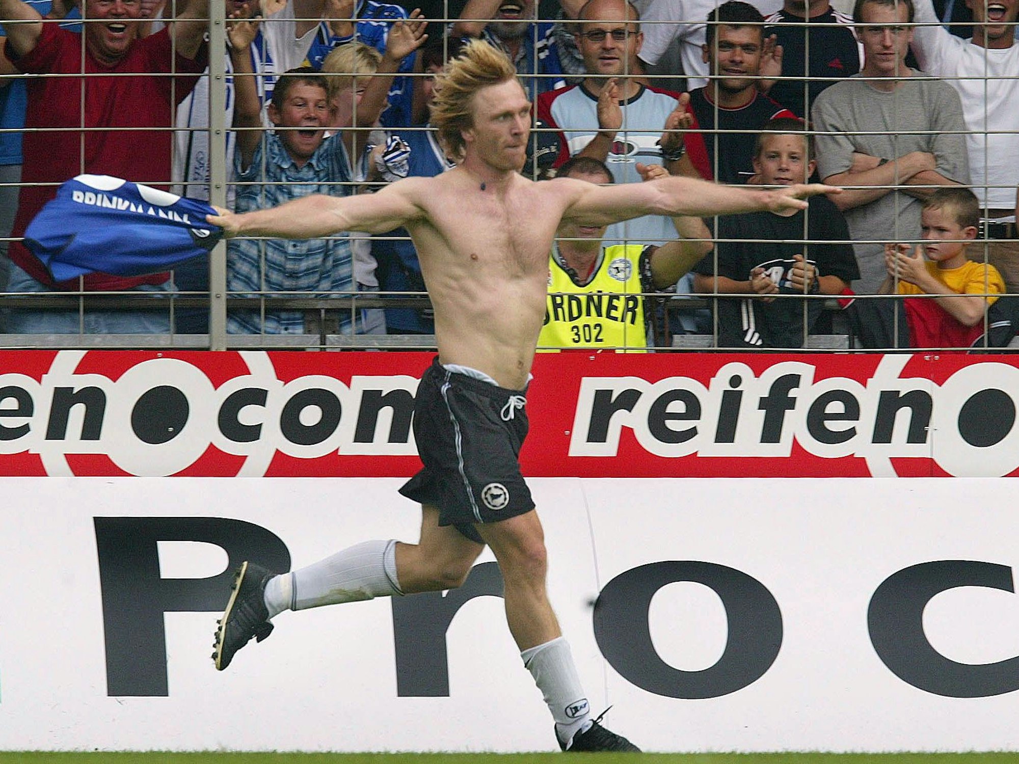 Ansgar Brinkmann damaliger Fußball-Bundesligaspieler von Arminia Bielefeld, läuft am 24.08.2002 in Bielefeld (Nordrhein-Westfalen) nach seinem Treffer zum 1:0 gegen den VfL Wolfsburg mit nacktem Oberkörper über den Platz.