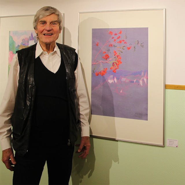 Der Kunstprofessor Hans Günter Hoffmann steht neben zwei Aquarellen von Kronenburg.