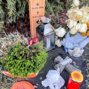 Das Bild zeigt den Gedenkort einer jungen Frau, die in Euskirchen bei einem Verkehrsunfall ums Leben gekommen ist. Vor dem Kreuz stehen Kerze und Blumen.