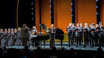 Das Foto zeigt den Chor der Kölner Oper unter der Leitung von Rustam Samedov und Solistin Maria Möller.