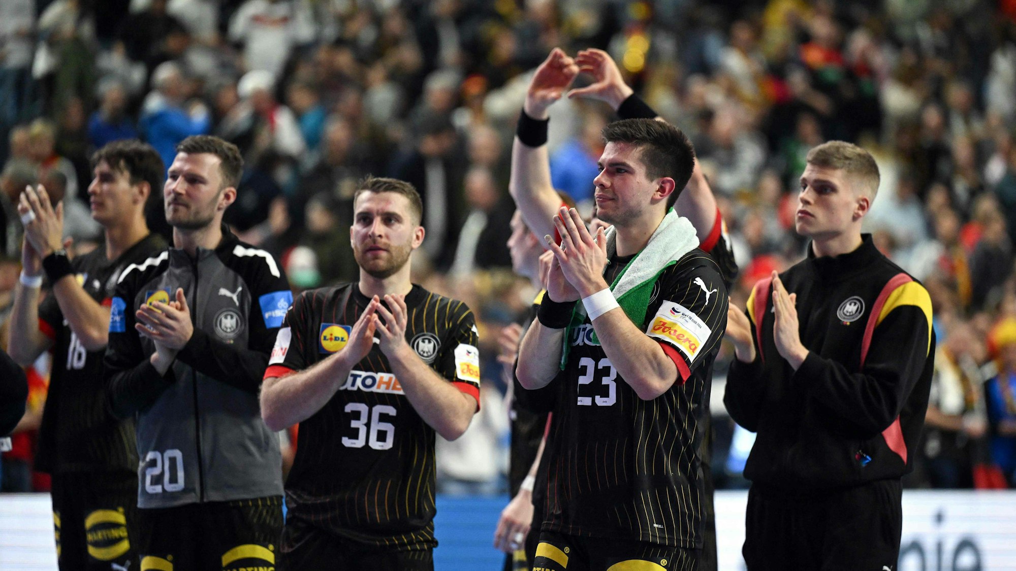 Germany's right back #23 Renars Uscins (2R) and team mates celebrate at the end of the Men's EURO 2024 EHF Handball European Championship main round match between Germany and Croatia in Cologne, western Germany on January 24, 2024. Croatia won the match 30-24. (Photo by INA FASSBENDER / AFP)