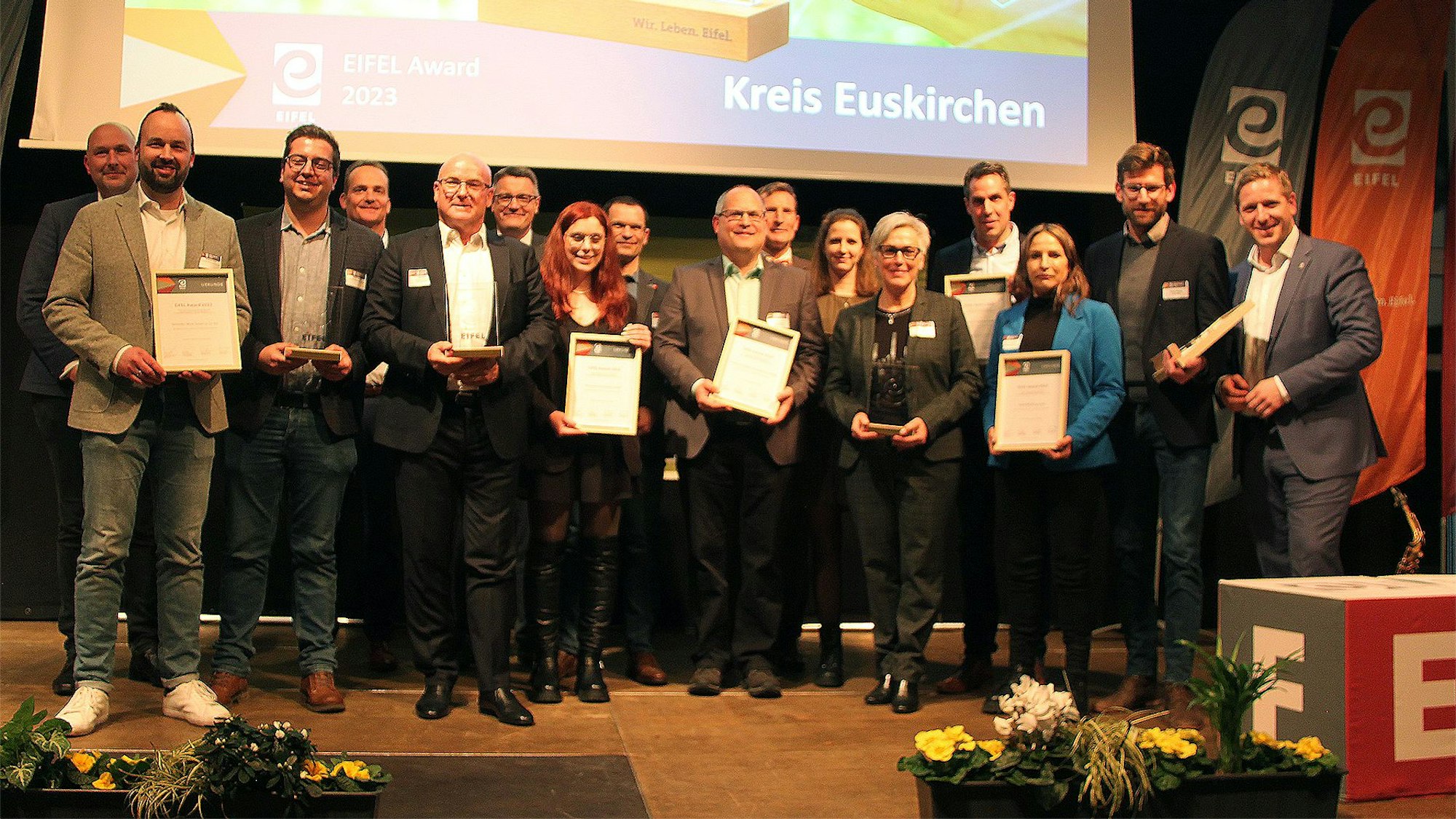 Mit Urkunden stehen die Gewinner des diesjährigen Eifel Awards auf der Bühne.