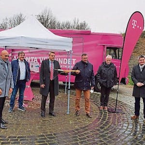Der damalige Niederkasseler Bürgermeister Stephan Vehreschild und Vertreter von Telekom, Politik und Stadtverwaltung stehen vor einem magentafarbenen Infomobil der Telekom.