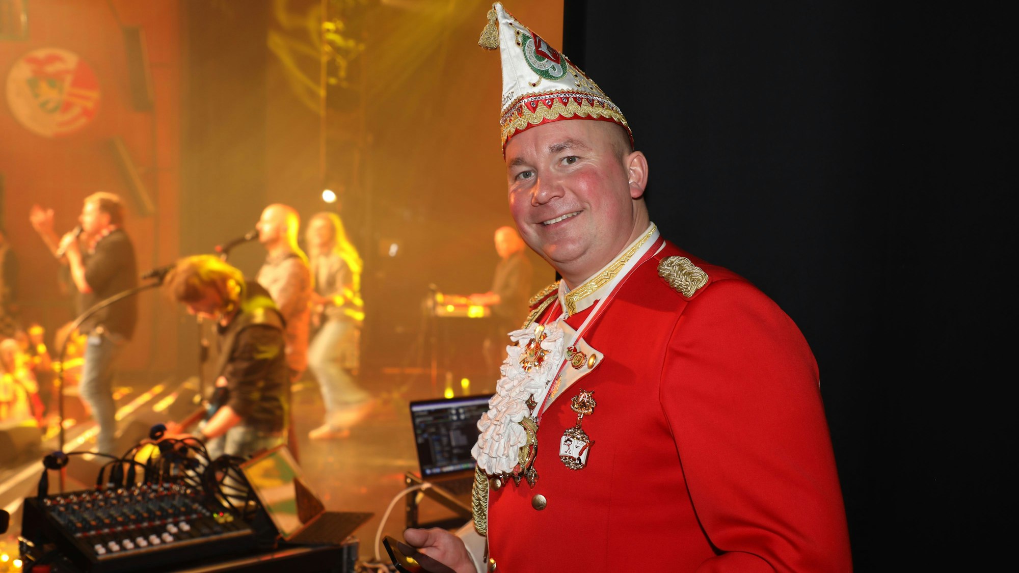 Prinzengarde-Geschäftsführer Philip Wallraf steht am Rand der Bühne im BErgischen Löwen. Auf der Bühne spielen die Bläck Fööss.
