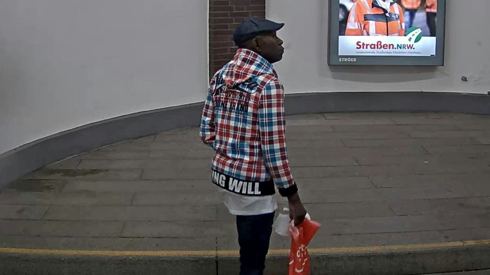 Der unbekannte Mann läuft am 9. Juni 2020 mit einer roten Plastiktüte durch den Bahnhof Köln-Deutz/Messe.