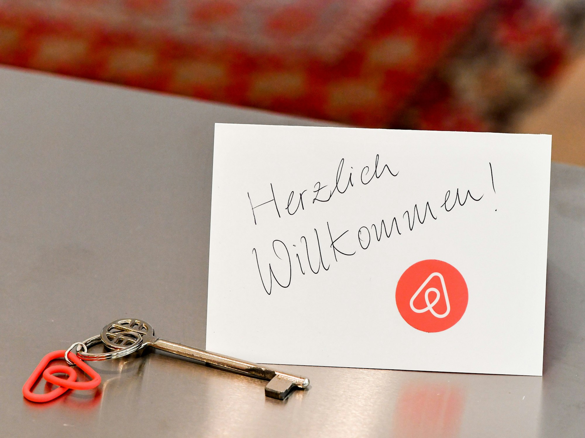 Ein Schlüssel mit einem Airbnb-Anhänger und eine Herzlich-Willkommen-Karte liegen in der Wohnung eines Airbnb-Gastgebers für den Gast bereit.