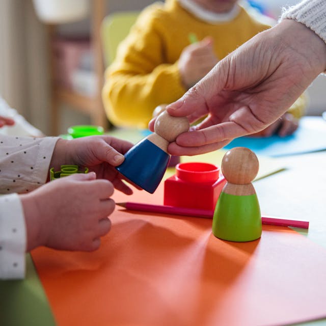 Kinder spielen mit Holzfiguren im Kindergarten
Getty Images / Lourdes  Balduque