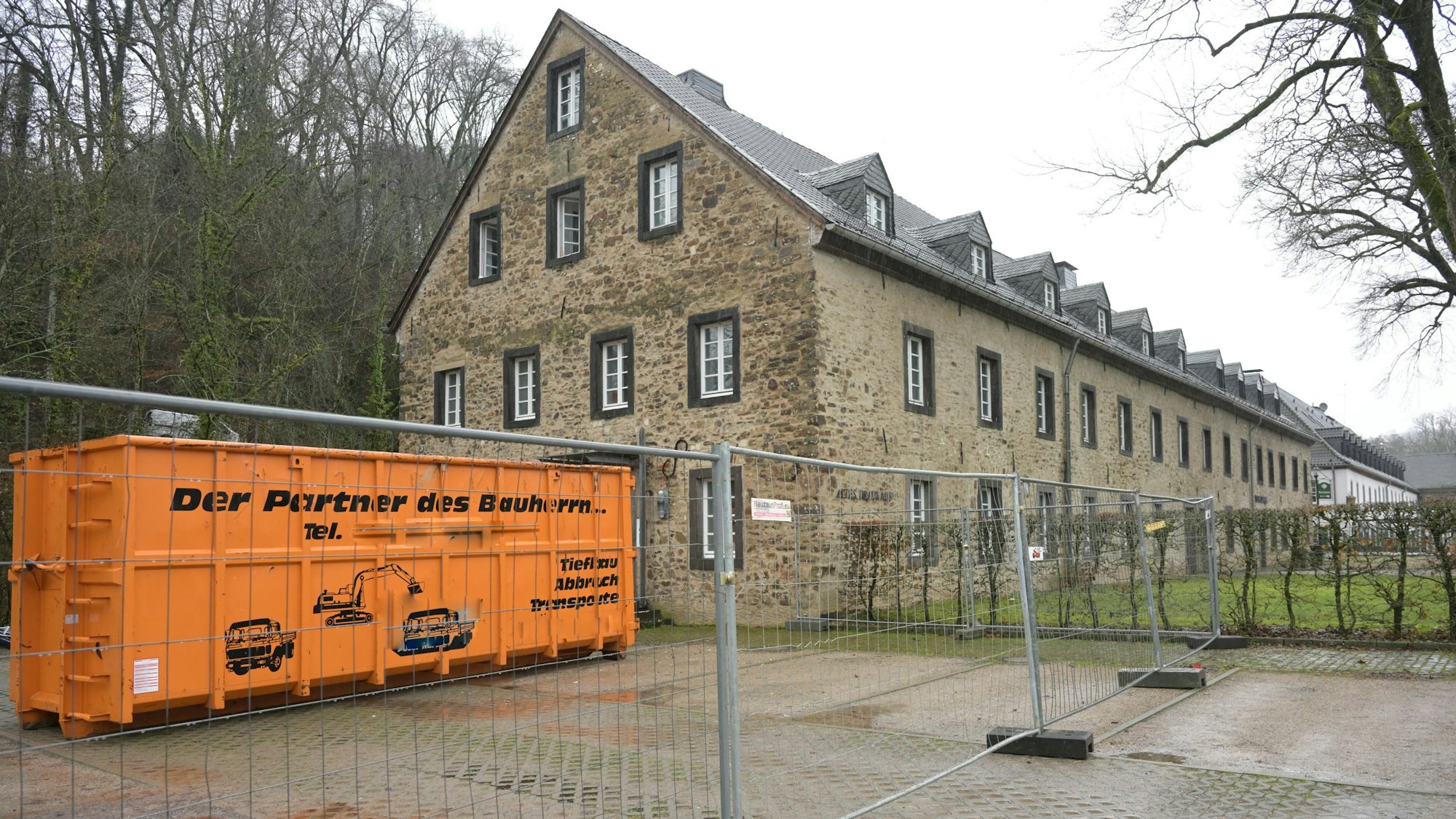 Altes Brauhaus in Altenberg mit Baucontainer, umgeben von einem Bauzaun.