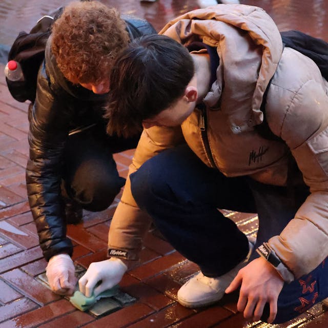Zwei Schüler reinigen Stolpersteine in der Opladener Fußgängerzone.