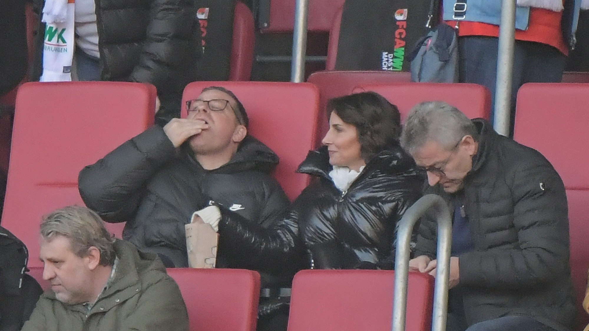 Max Eberl und seine Lebensgefährtin Natascha Fruscella essen beim Spiel des FC Bayern in Augsburg Popcorn.