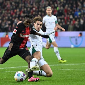 Leverkusens Jeremie Frimpong (l) und Mönchengladbachs Florian Neuhaus kämpfen um den Ball.