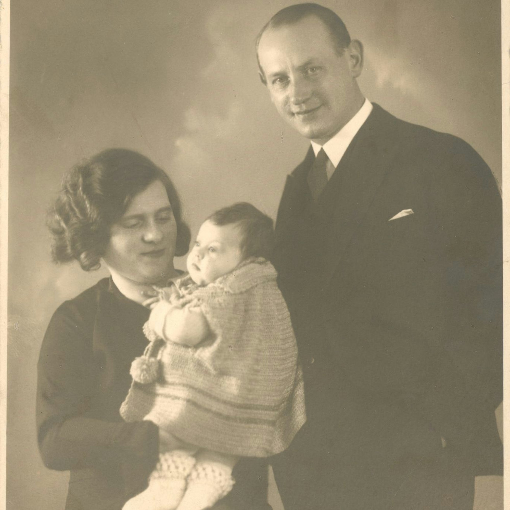 Ein Schwarz-Weiß-Foto eines Ehepaares. Die Frau hat ein kleines Mädchen auf dem Arm.