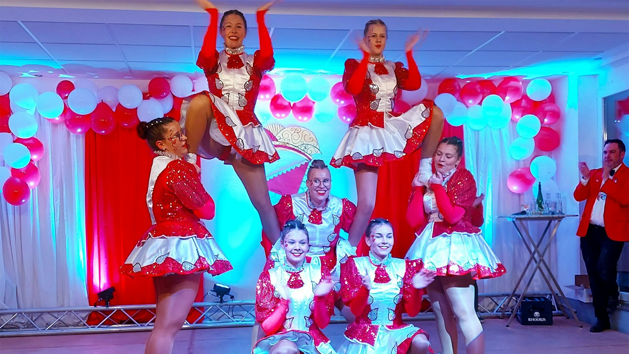 Sieben junge Frauen der Tanzgarde zeigen eine Akrobatische Pose auf einer Bühne.