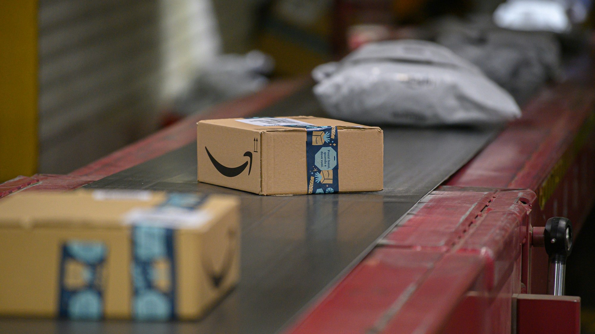 Amazon Pakete liegen im DHL-Paketzentrum auf einem Transportband.