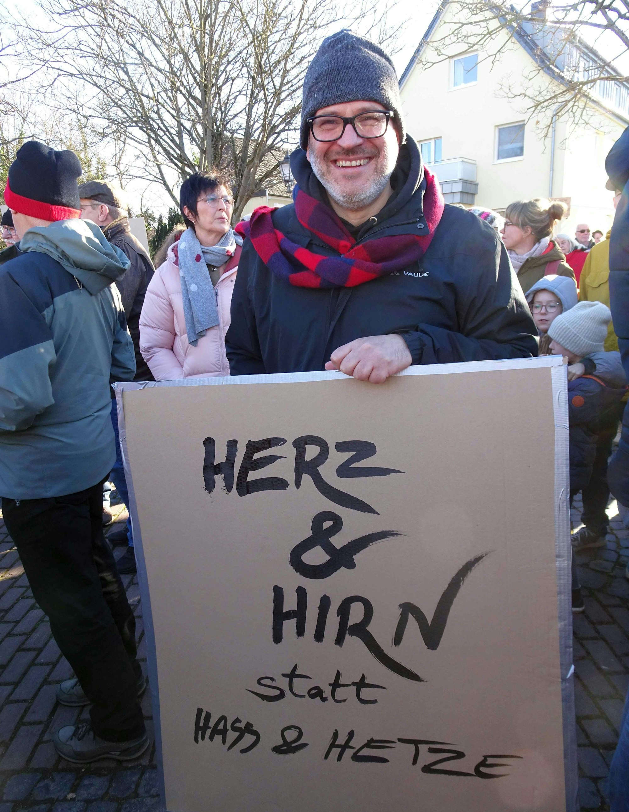 Demonstrant Gero Hartwig hält sein selber gefertigtes Pappschild in die Höhe: "Herz & Hirn statt Hass und Hetze"