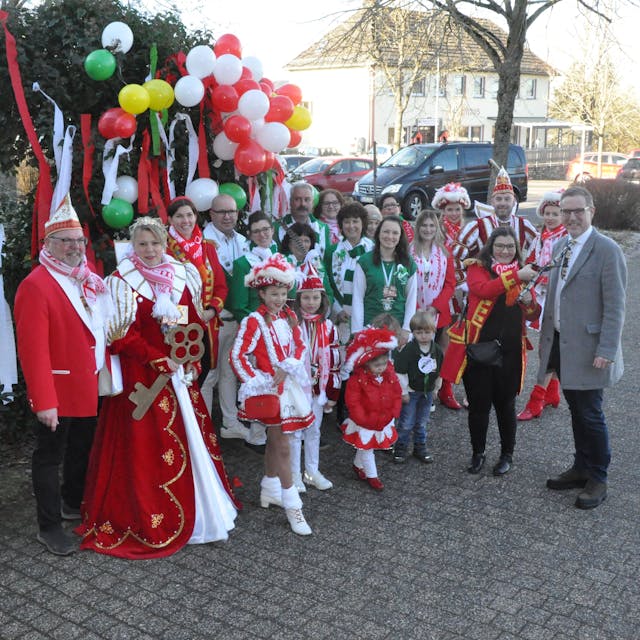 Vertreter und Vertreterinnen der Karnevalsgesellschaften und -vereine der Gemeinde Nettersheim stehen vor einem mit Luftballons und Krepppapier geschmücktem Busch am Rathaus in Zingsheim.