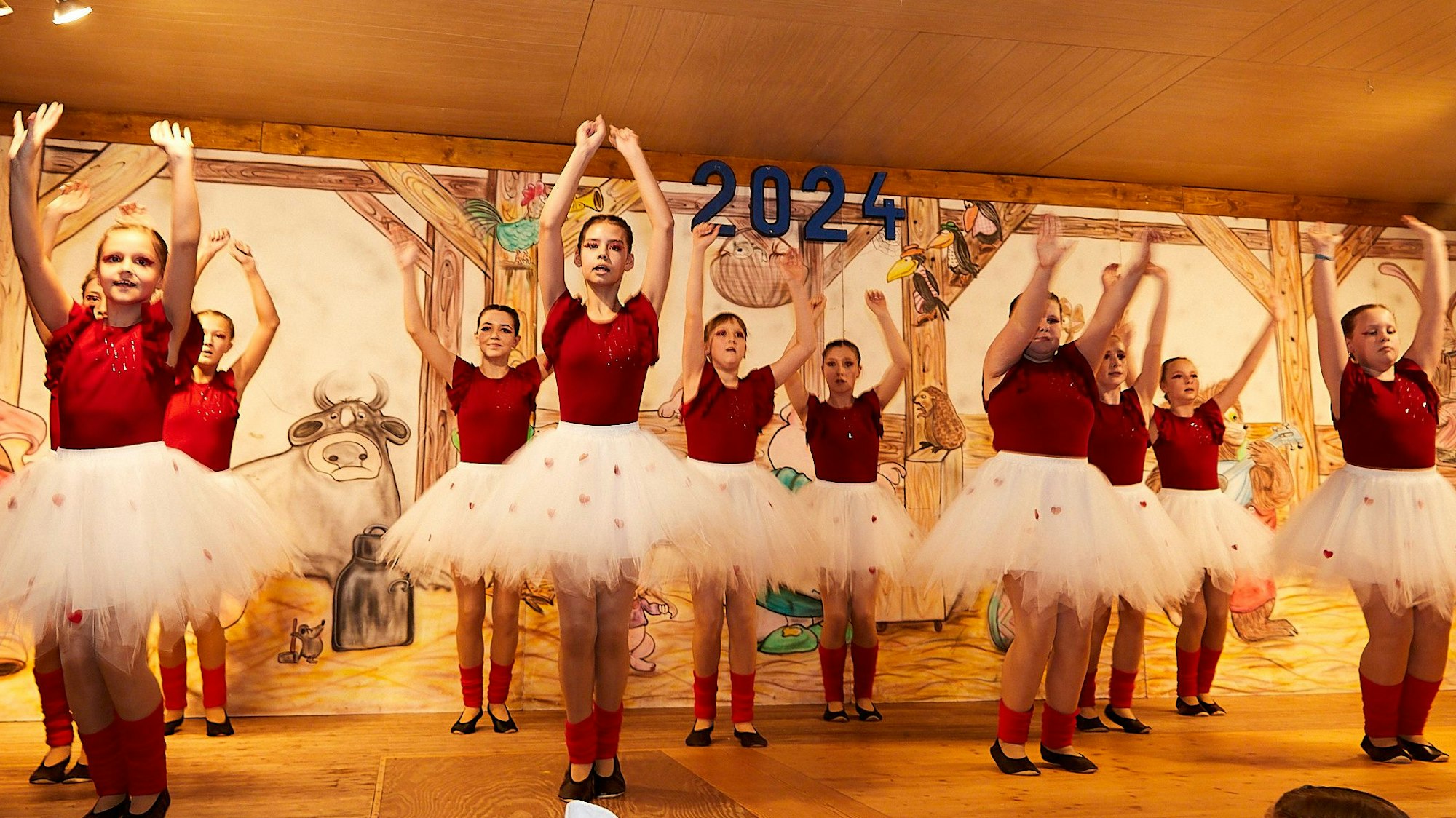 Eine Gruppe junger Mädchen tanzt in weißen Tüll-Röcken und roten T-Shirts auf einer Bühne.