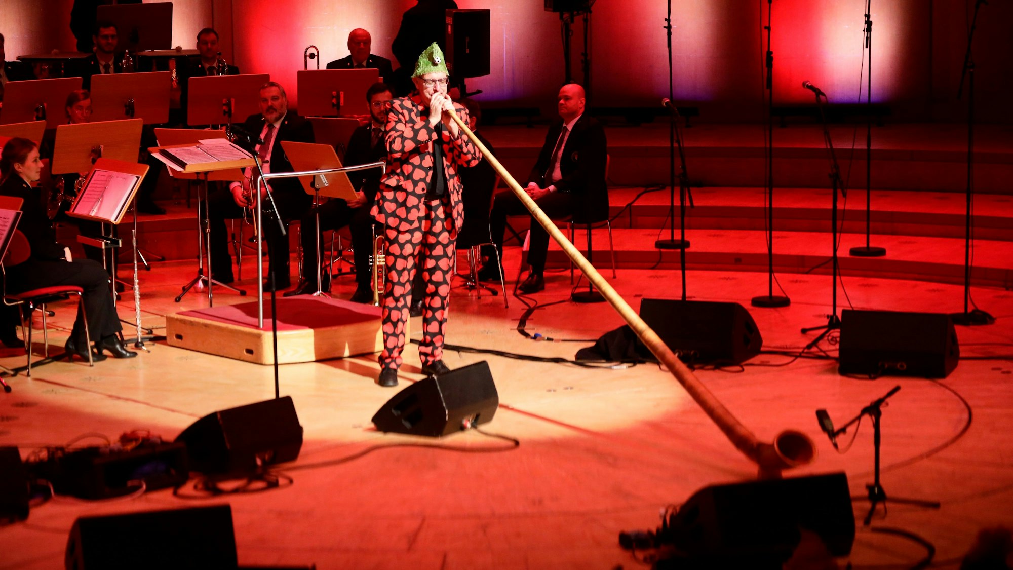 Ebasa Pallada, bekannt aus der alternativen Karnevalsveranstaltung „Deine Sitzung“, mit Alphorn auf der Bühne.