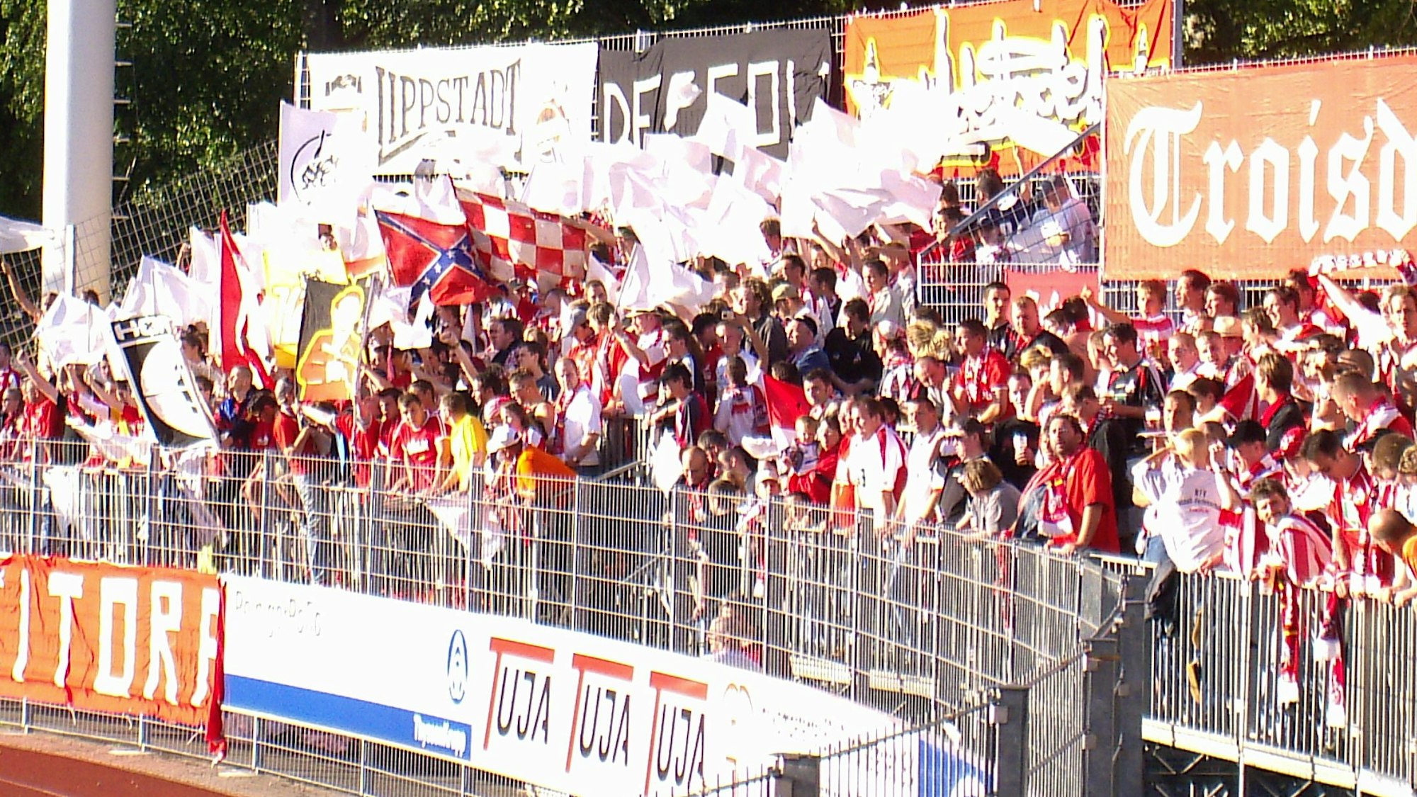 In einer Fankurve wedeln Fußball-Anhänger mit weißen und roten Fähnchen.
