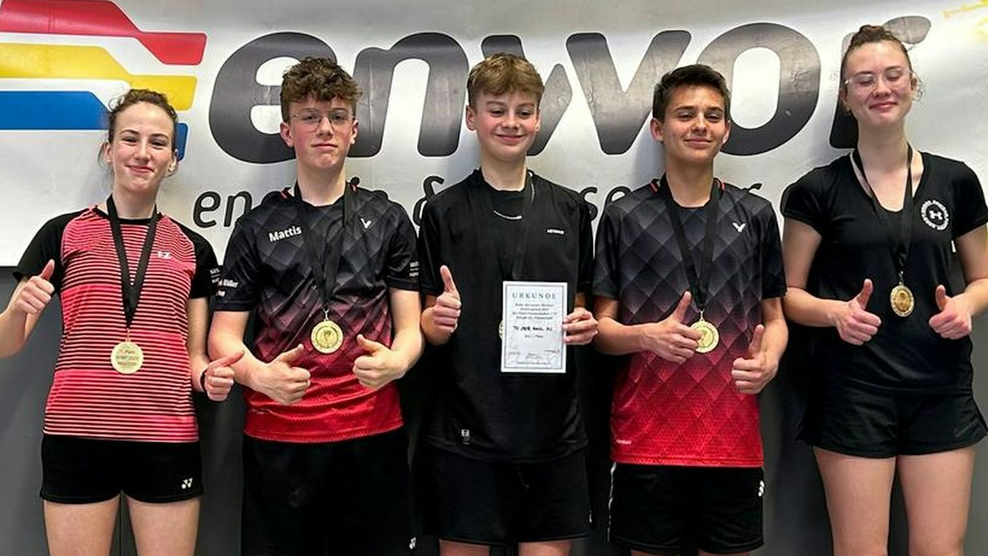 Die fünf Spieler der Badminton-Jugend des TV Kall stehen mit erhobenen Daumen nebeneinander. Sie tragen Medaillen um den Hals, ein Spieler hält eine Urkunde in der Hand.