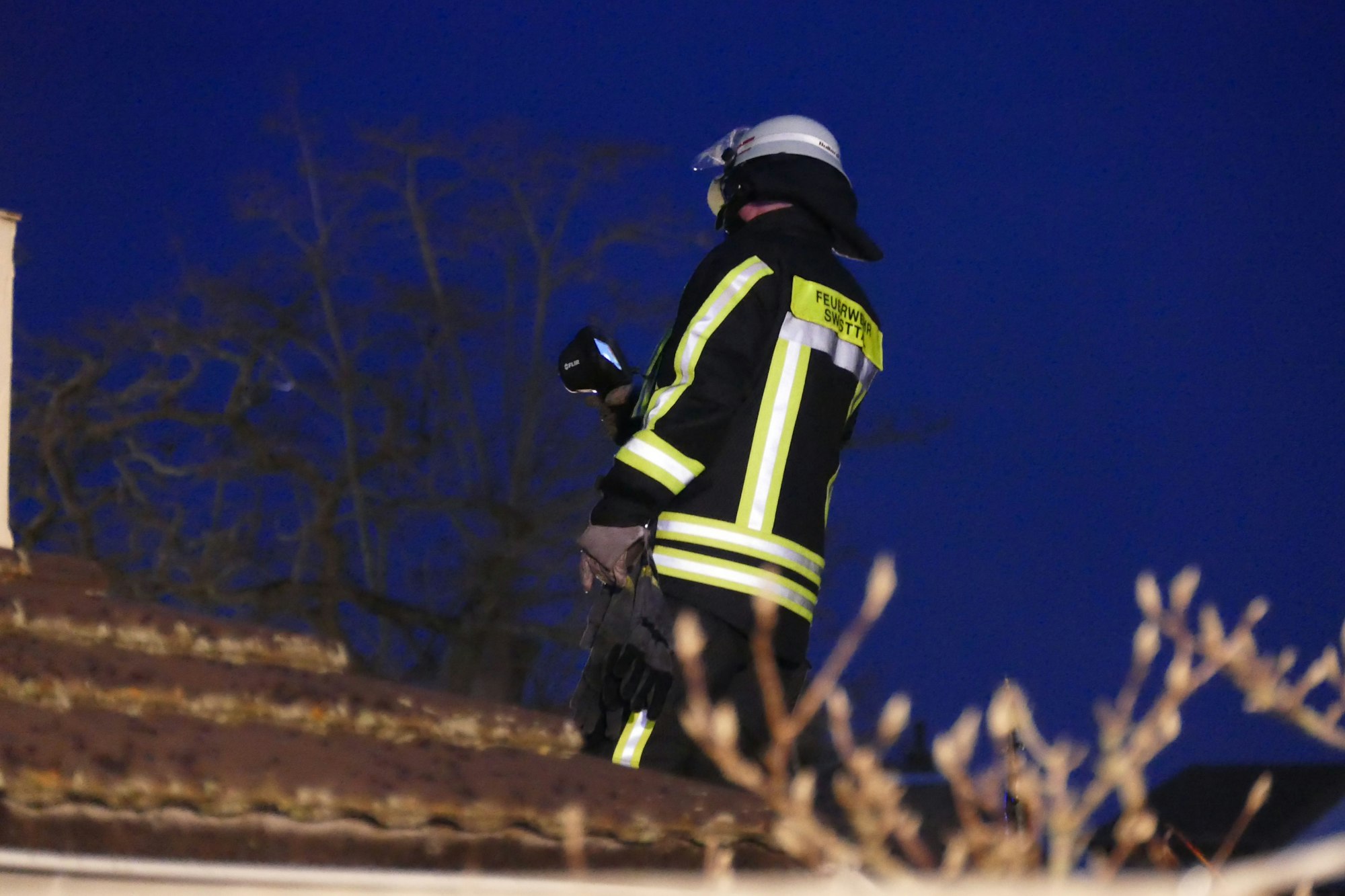 Ein Feuerwehrmann steht auf einem Dach.
