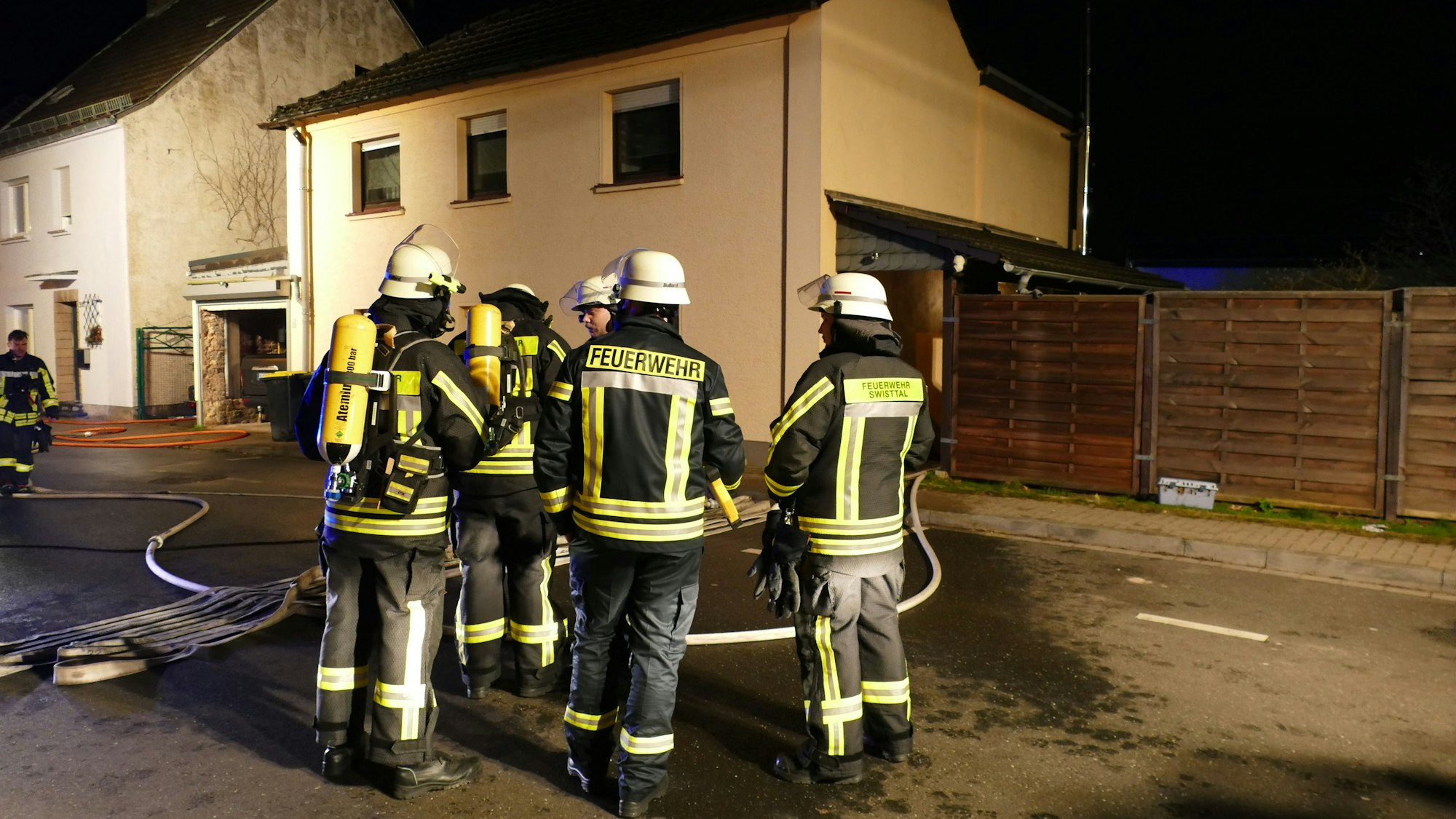 Feuerwehrleute stehen vor einem Haus.