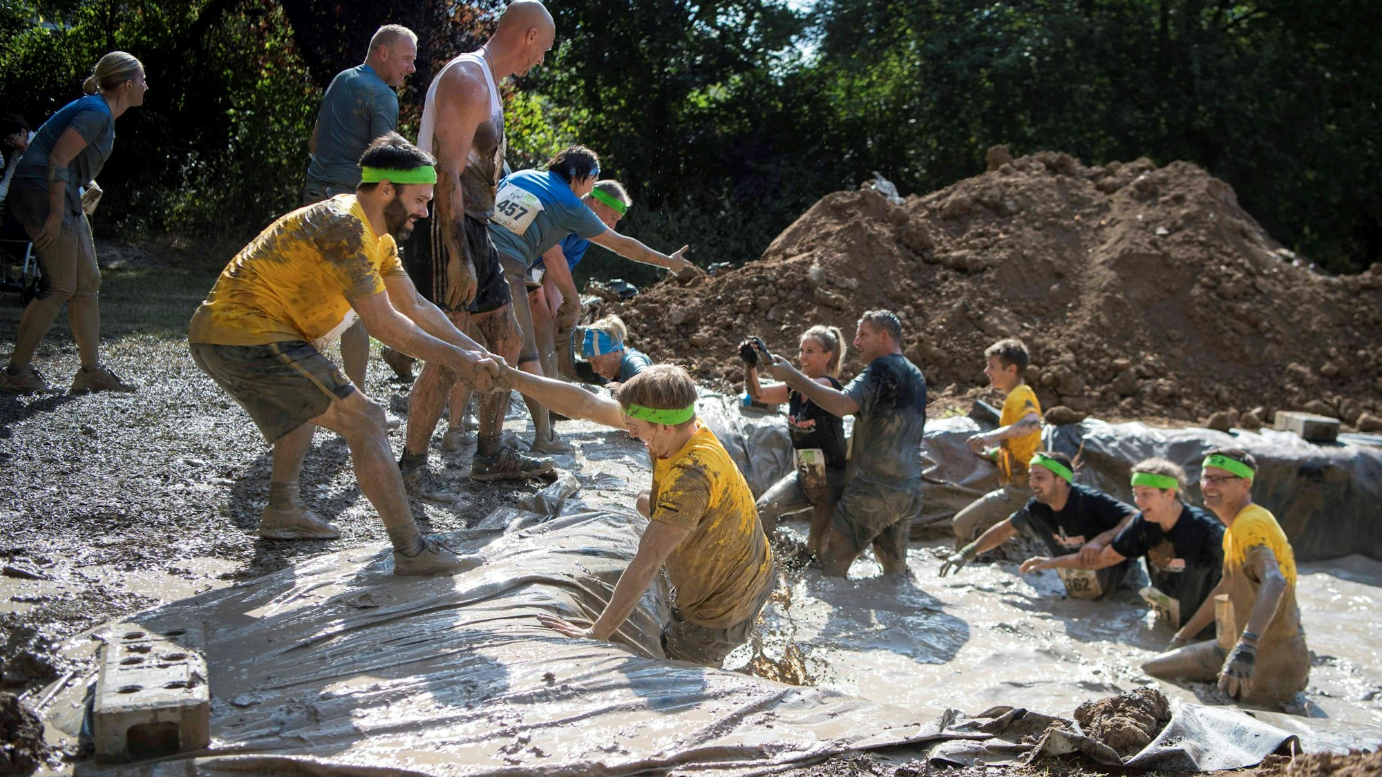 Das Bild zeigt ein Hindernis beim Max-Buddels-Lauf. Auf einem mit Wasser gefüllten Graben kommen die Teilnehmer einfacher heraus, wenn sie sich helfen.