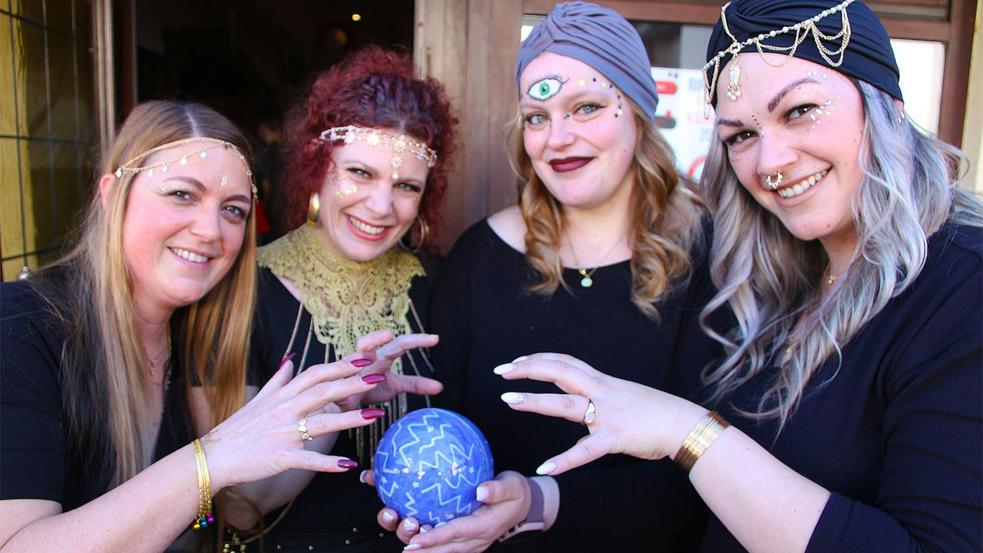 Vier verkleidete junge Frauen präsentieren eine blaue Kugel.