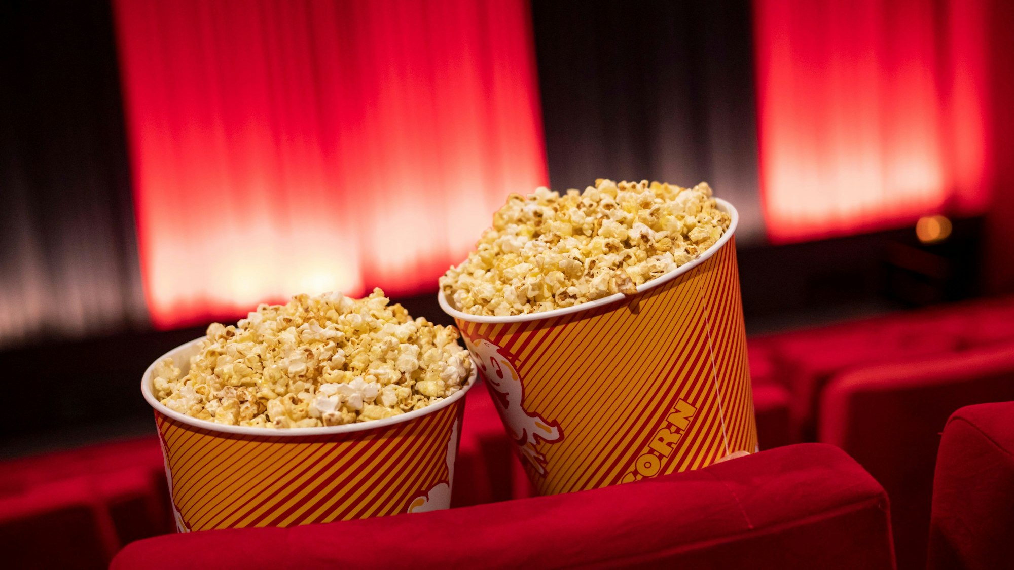 Popcorn steht zwischen den Sitzreihen in einem Kino