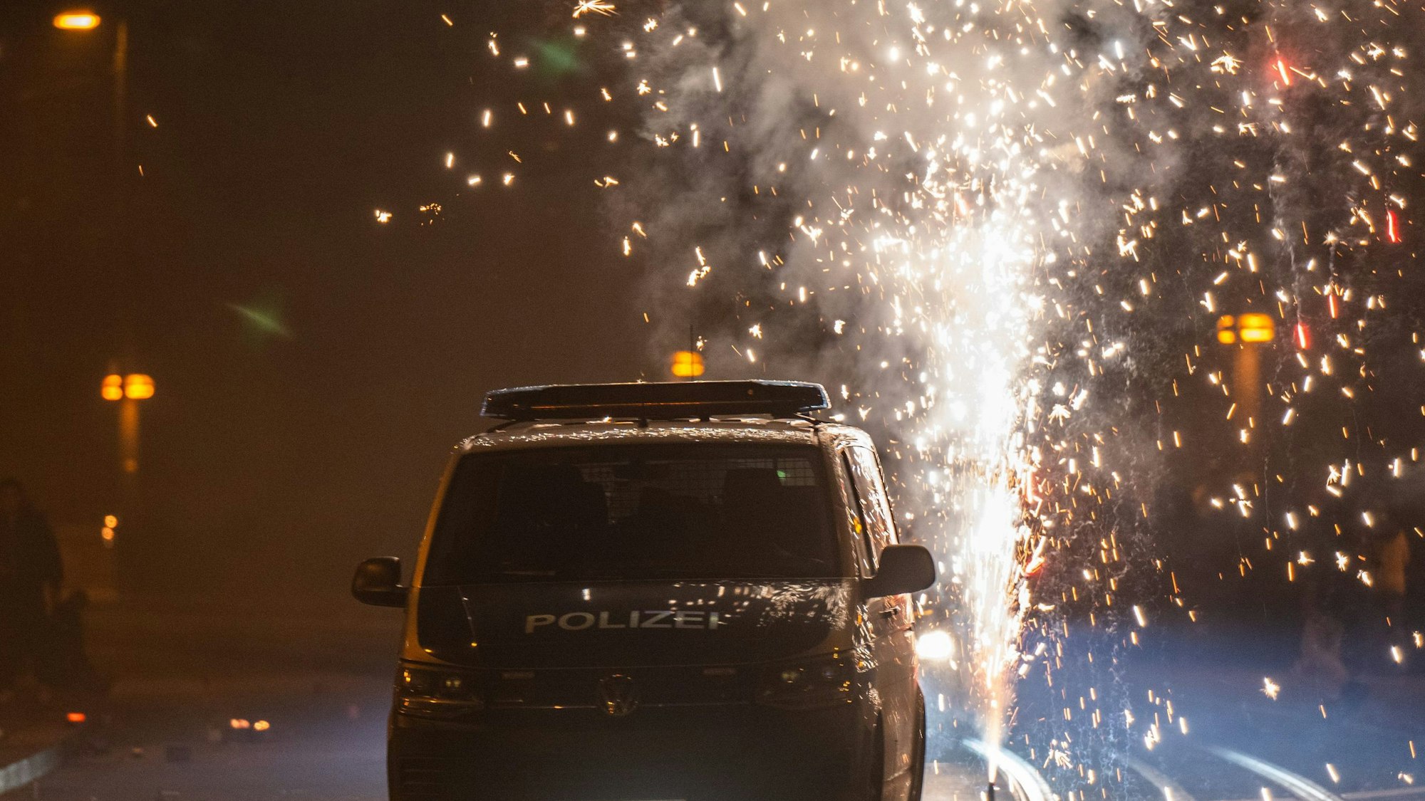Hinter einem Polizeiauto wird Feuerwerk gezündet.