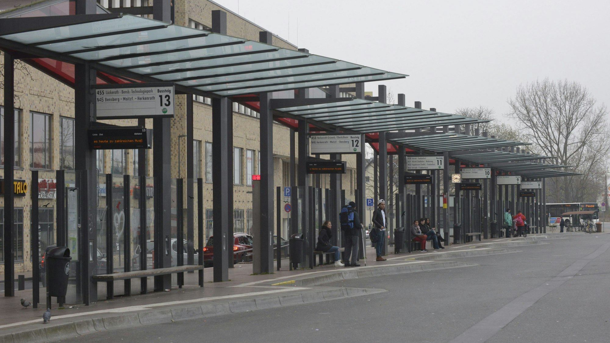 Am Gladbacher Busbahnhof warten einige Fahrgäste, im Hintergrund ist lediglich ein Bus zu sehen.