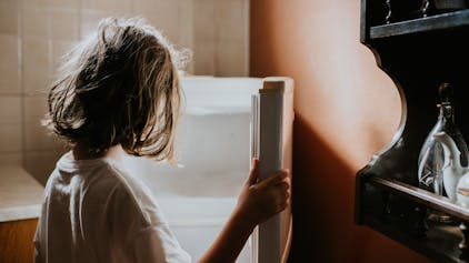 Ein kleines Mädchen steht vor einem leeren Kühlschrank.