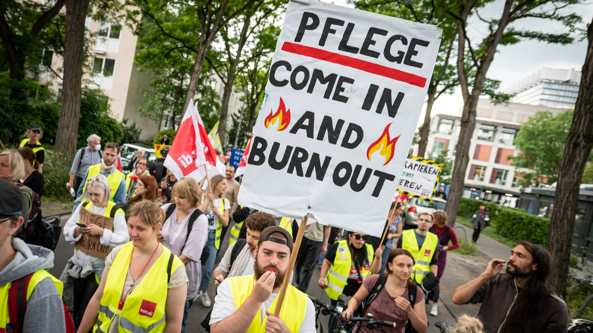 Mit einem Plakat „Pflege - come in and burn out“ nehmen Pflegekräfte an einer Demonstration teil.