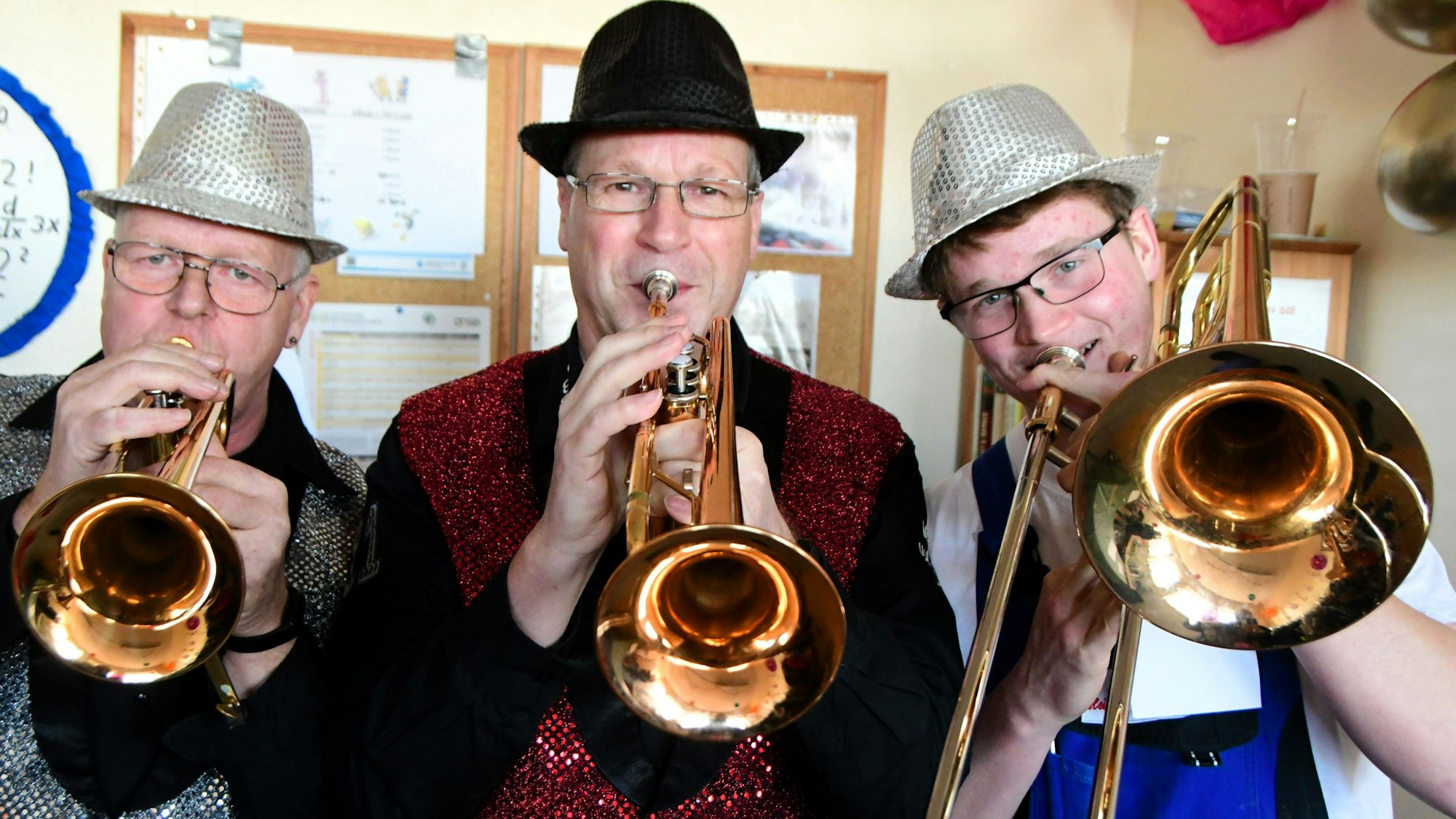 Ein kostümiertes Musikertrio, bestehend aus zwei Trompetern und einem Posaunisten.