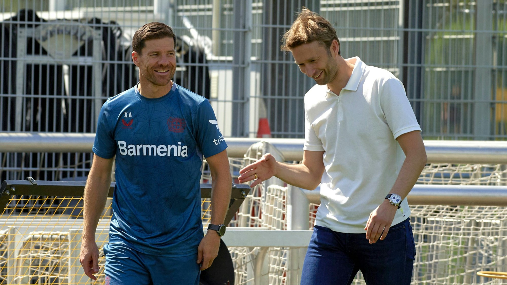 Simon Rolfes und Xabi Alonso lachen bei einem Gespräch auf dem Trainingsplatz.