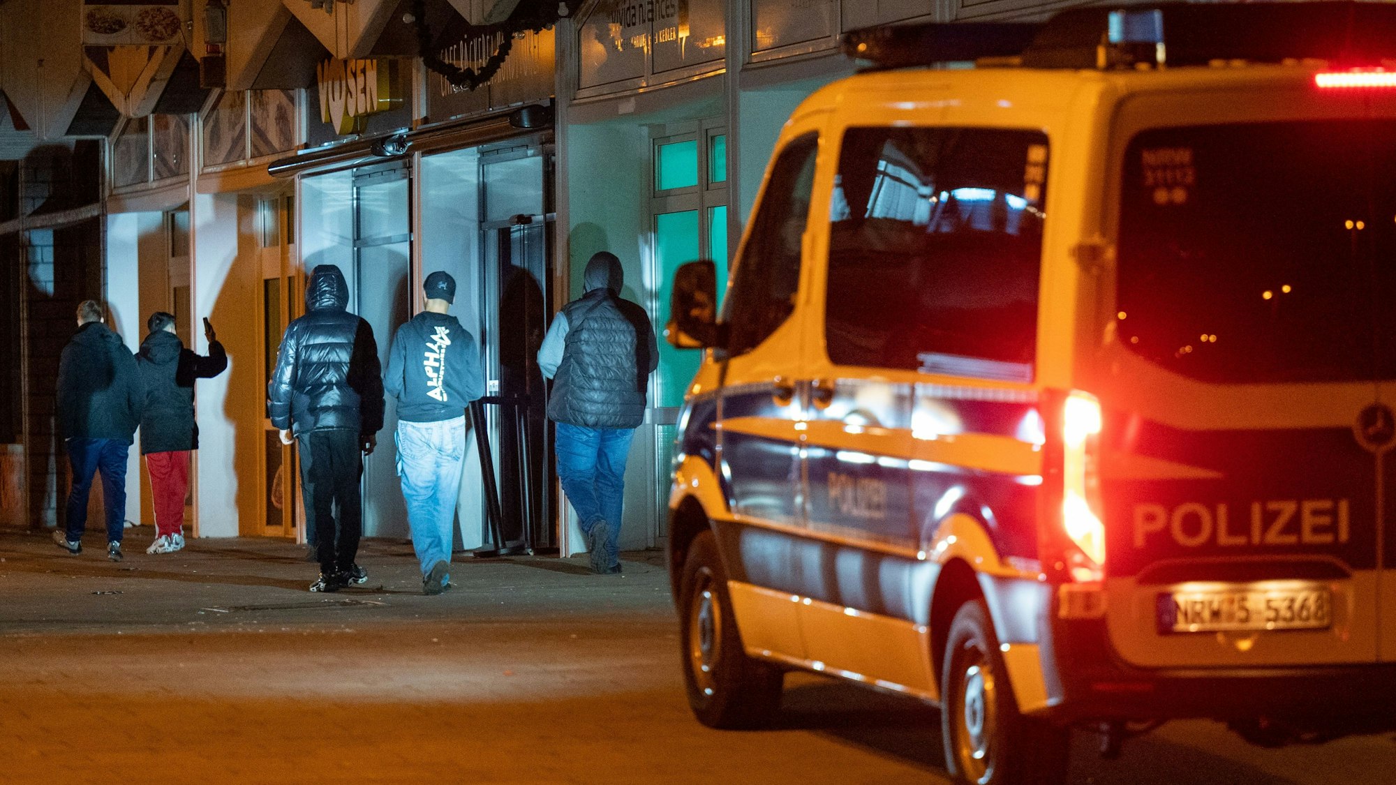Ein Polizeiwagen fährt durch das Görlinger-Zentrum in der Nacht. Im Scheinwerferlicht stehen Jugendliche.